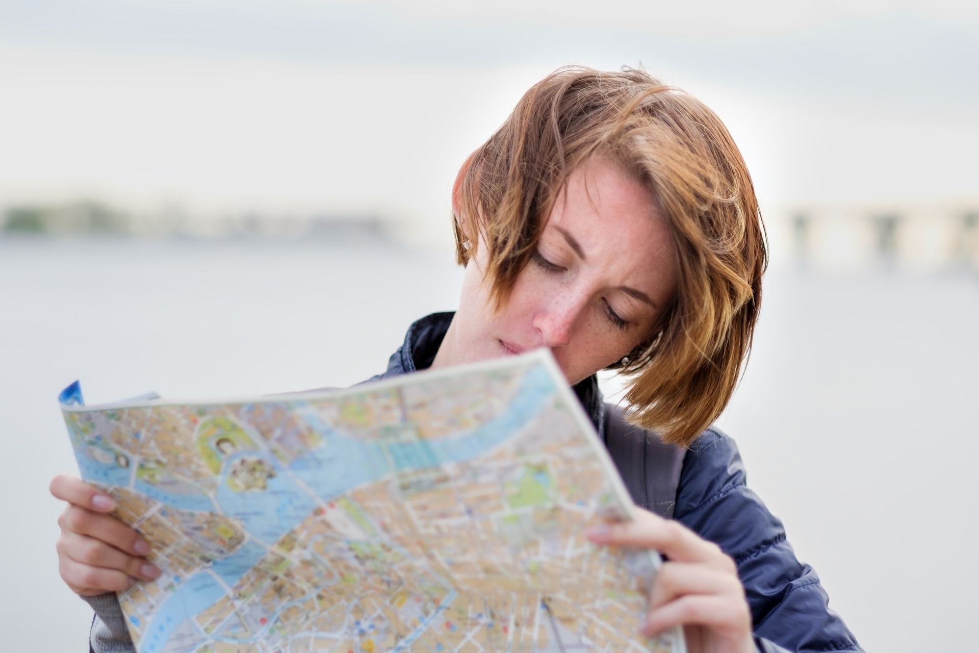 A beautiful girl in a denim jacket is holding a map and trying to understand where she is. Lost in an unfamiliar city. Making a route for the excursion. A beautiful girl in a denim jacket is holding a map and trying to understand where she is. Lost in an unfamiliar city. Making a route for the excursion.